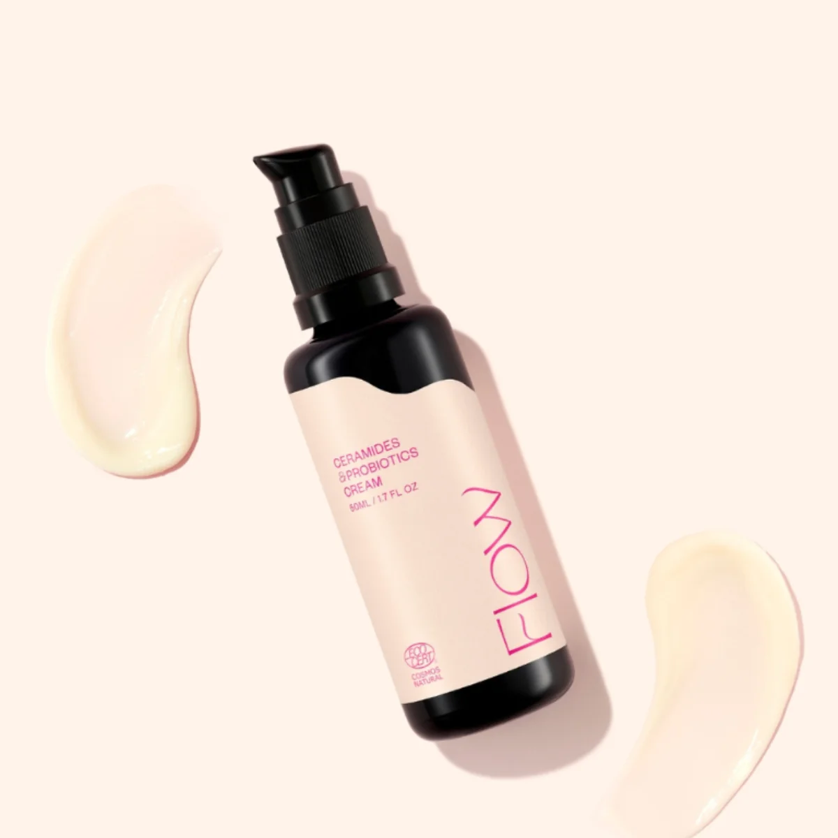 Pump bottle labeled 'Ceramides & Probiotics Cream' on a pale pink background with two cream swirls nearby, product shot.