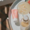 Coral SPF 50 sunscreen tube on a white tray beside a glass of iced drink and fruit.