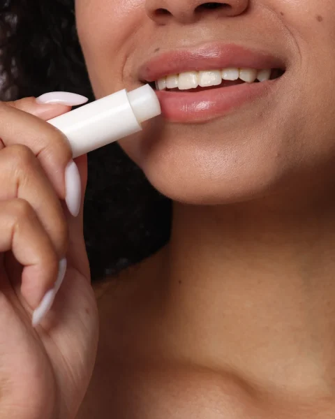 Close-up of a person applying a white lip balm stick to their lips.